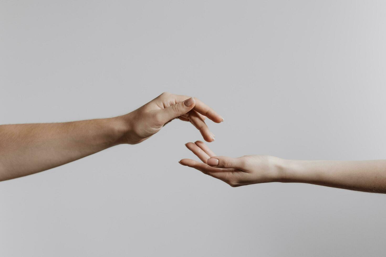 Hands touching each other isolated on grey background. Concept of human relation, community, togetherness, teamwork, love, symbolism, culture and history. photo