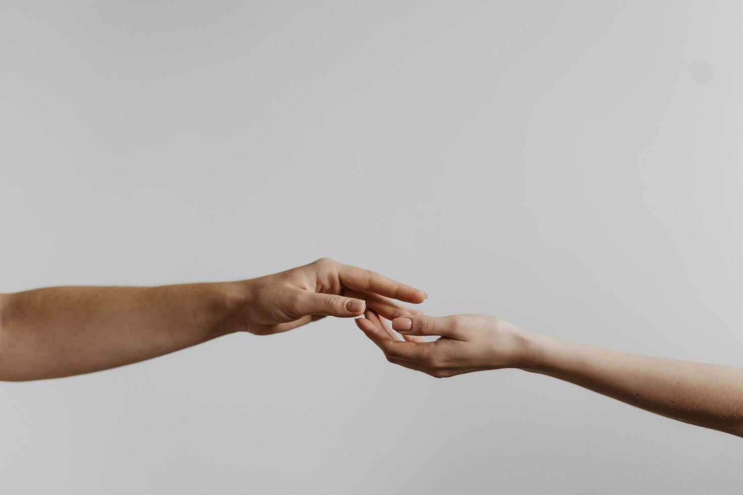 Fingers of Two People Nearly Touching. Beautiful man's and woman's hands touching each other isolated on grey background. Close up help hand. Helping hand concept, support. Friendly handshake. photo