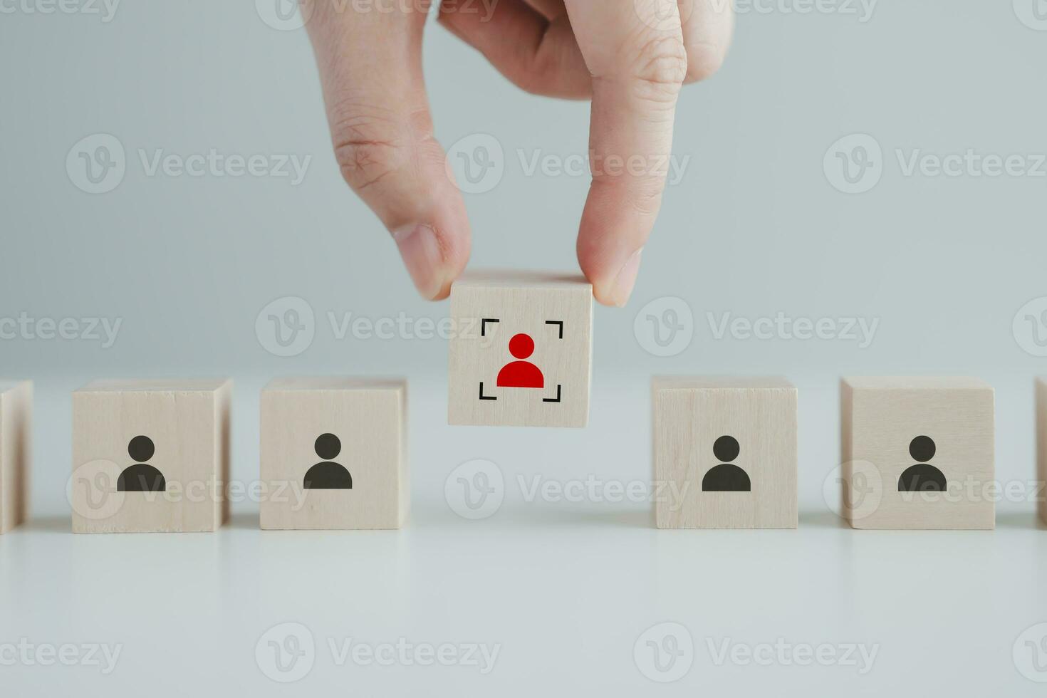 Hand choosing red human icon with focus frame on wood block. Choice of employee leader from crowd. Leadership, Business hiring, recruitment selection. Career opportunity. Human Resource Management. photo