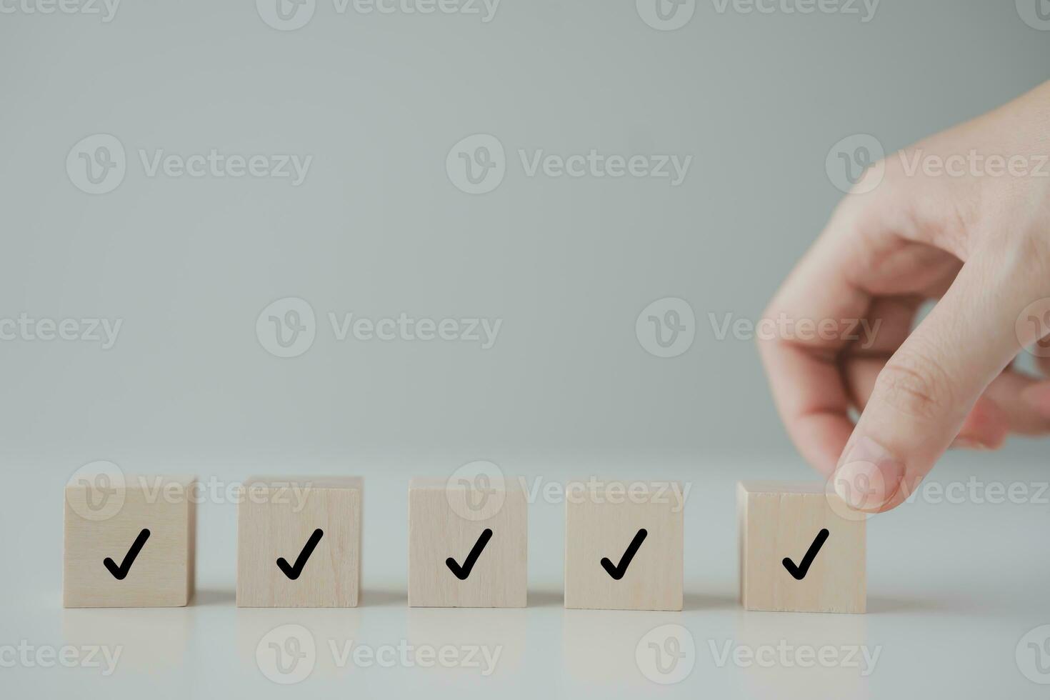 Checklist, Task list, Survey and assessment. Quality Control. Goals achievement and business success. Hand holding Check mark on wooden blocks for complete check list. photo