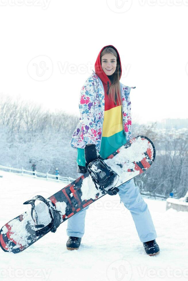 Young woman holding snowboard on her shoulders photo