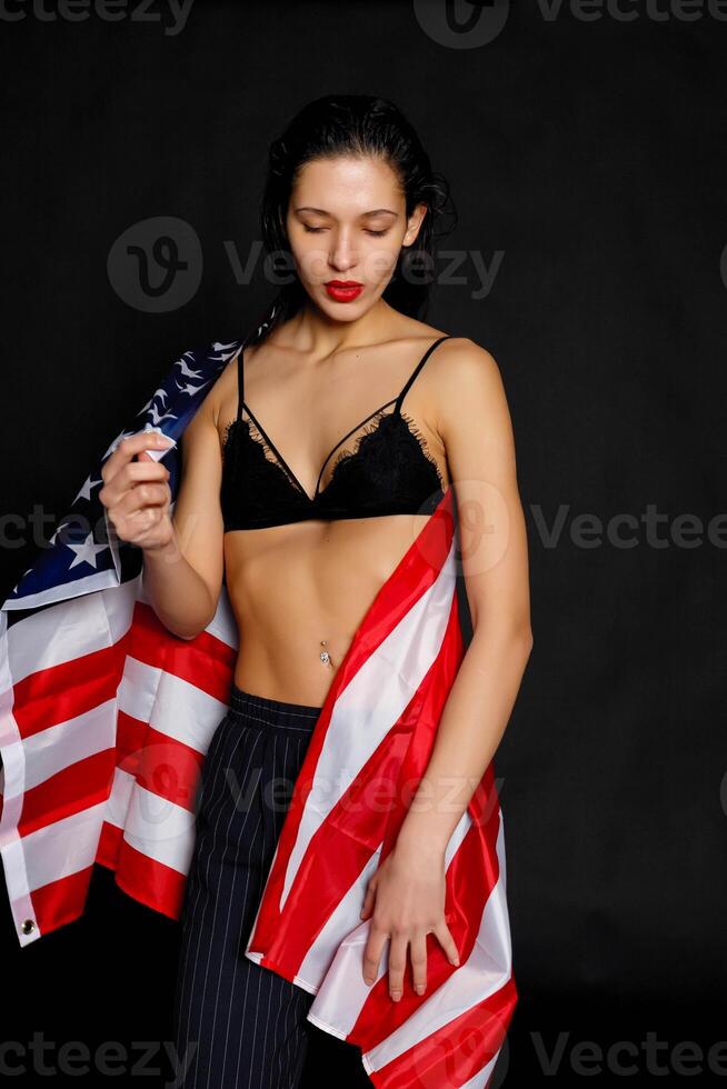 Portrait female athlete wrapped in American Flag against black background photo