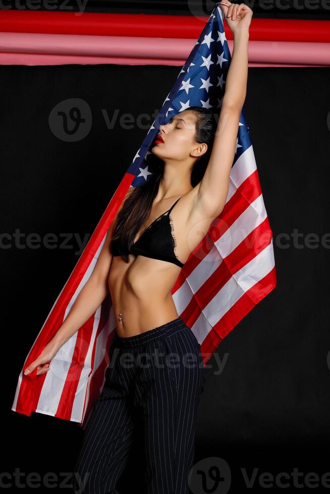 Portrait female athlete wrapped in American Flag against black background photo