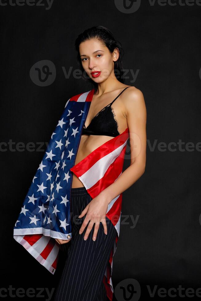 Portrait female athlete wrapped in American Flag against black background photo