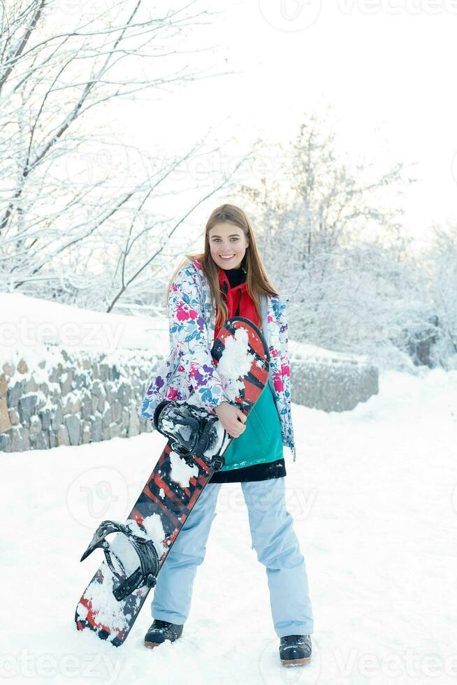 Young woman holding snowboard on her shoulders photo