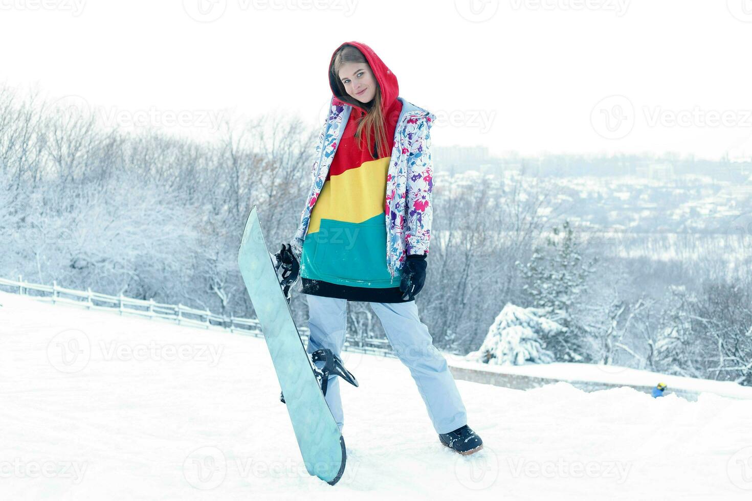 Young woman holding snowboard on her shoulders photo