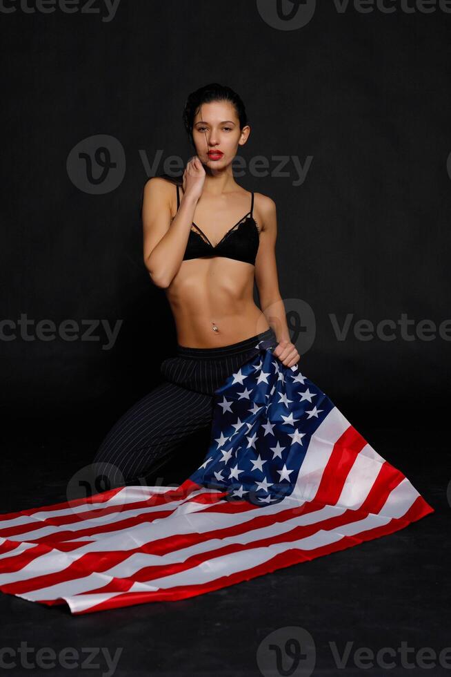 Portrait female athlete wrapped in American Flag against black background photo