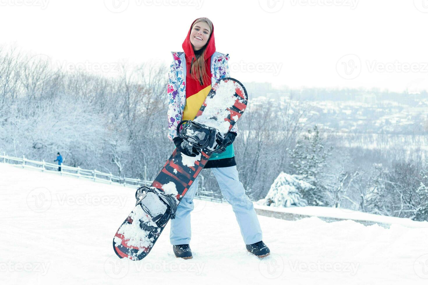 Young woman holding snowboard on her shoulders photo