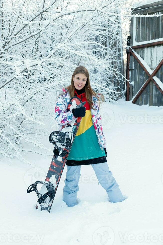 Young woman holding snowboard on her shoulders photo