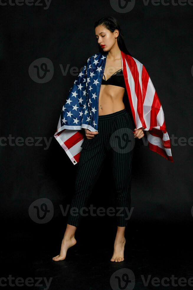 Portrait female athlete wrapped in American Flag against black background photo