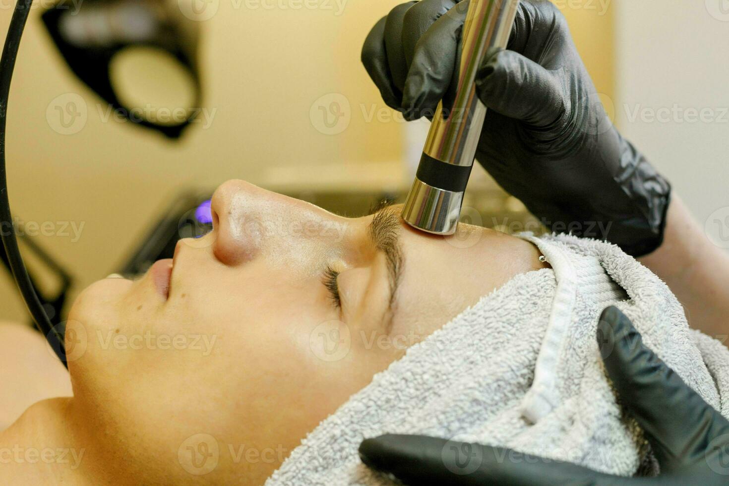 The cosmetologist makes the procedure ultrasonic face peeling photo