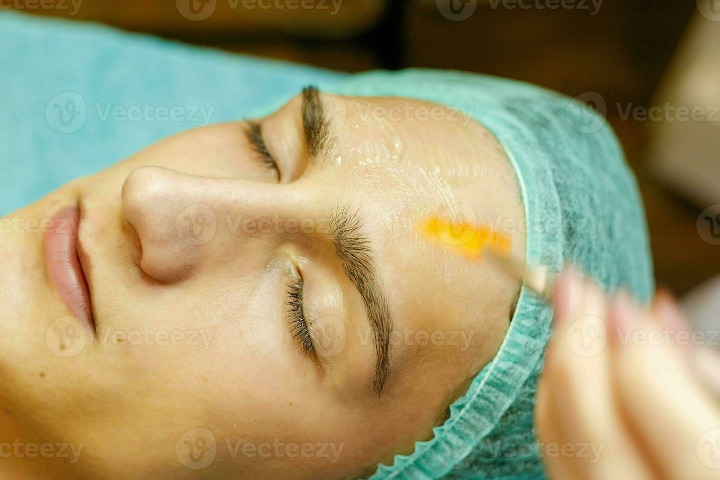The cosmetologist puts a mask on the face of a young man. photo