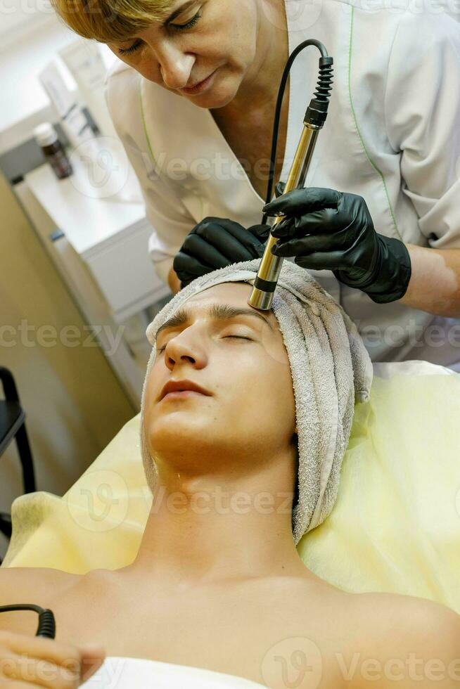 The cosmetologist makes the procedure ultrasonic face peeling photo