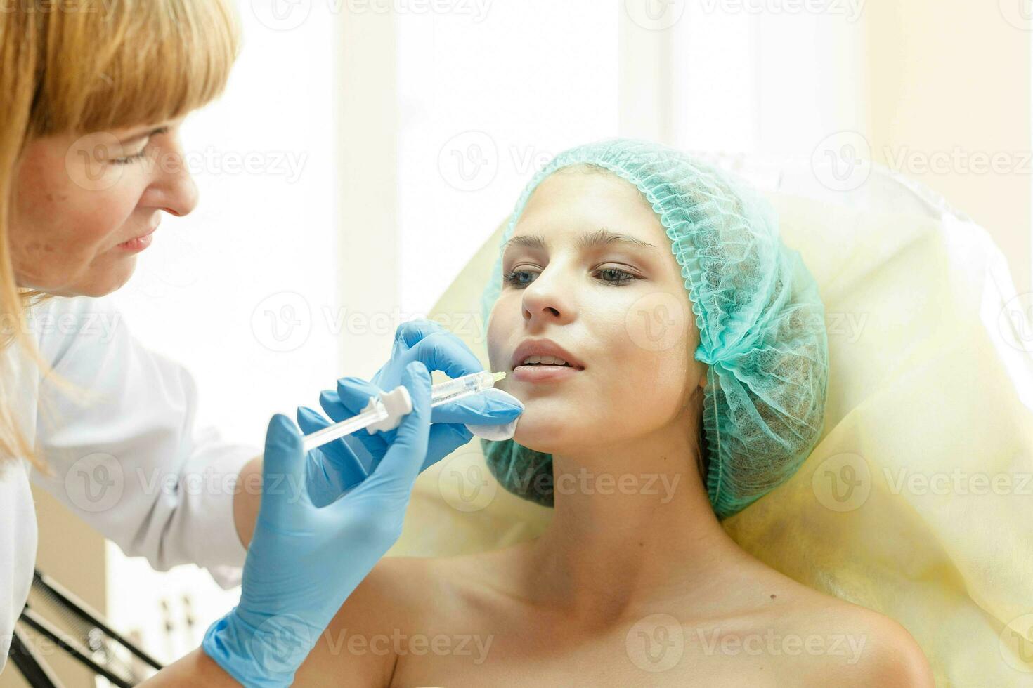 médico cosmetólogo hace inyecciones en el frente para paciente. foto