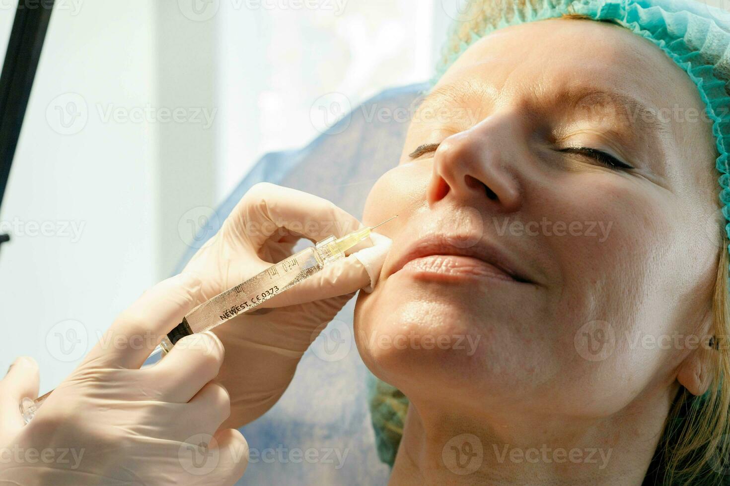 Doctor beautician makes injections in the forehead for patient. photo