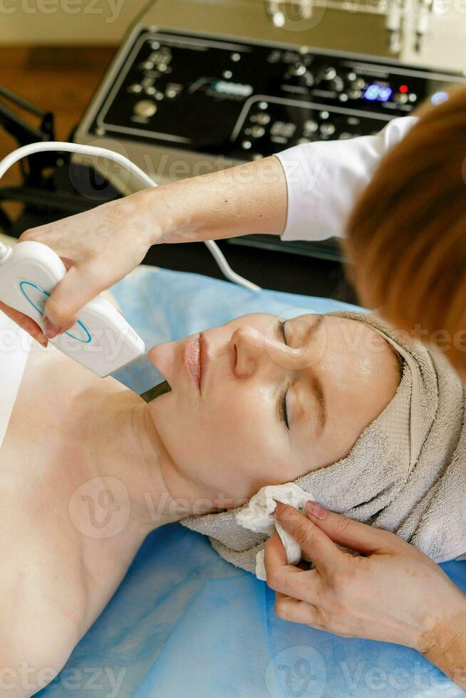 The cosmetologist makes the procedure ultrasonic face photo