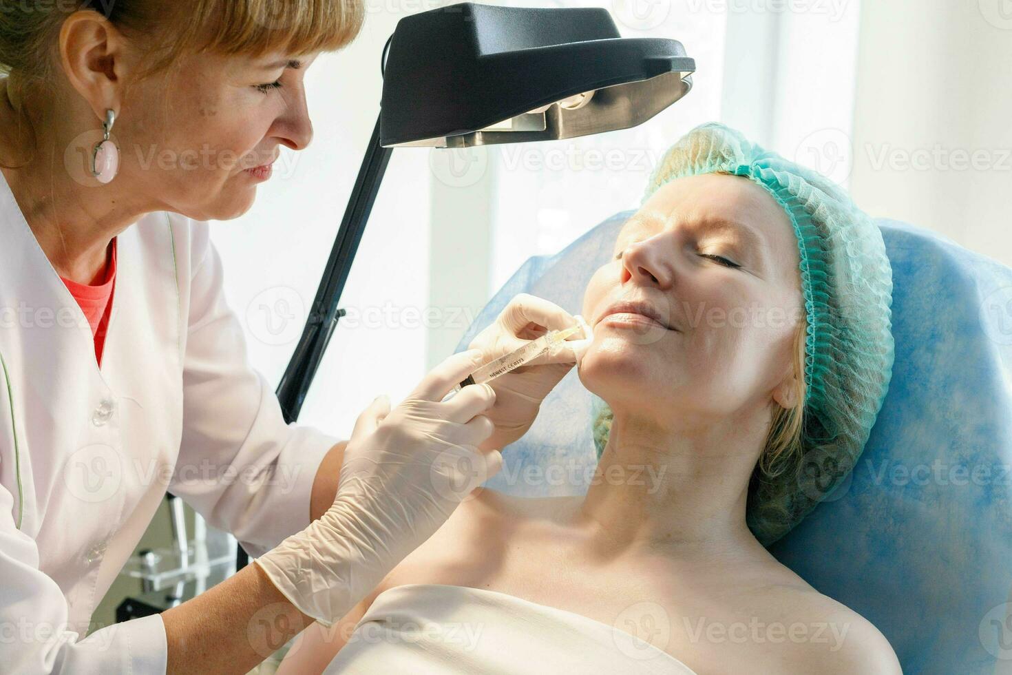 médico cosmetólogo hace inyecciones en el frente para paciente. foto