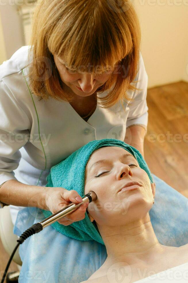 Cosmetologist makes the procedure microcurrent therapy in a beauty salon photo