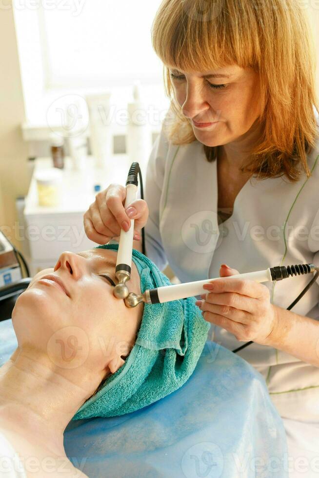 Cosmetologist makes the procedure microcurrent therapy in a beauty salon photo