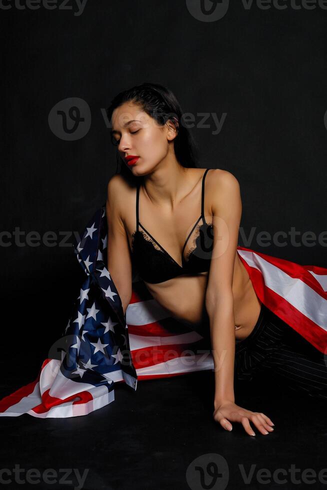 Portrait female athlete wrapped in American Flag against black background photo