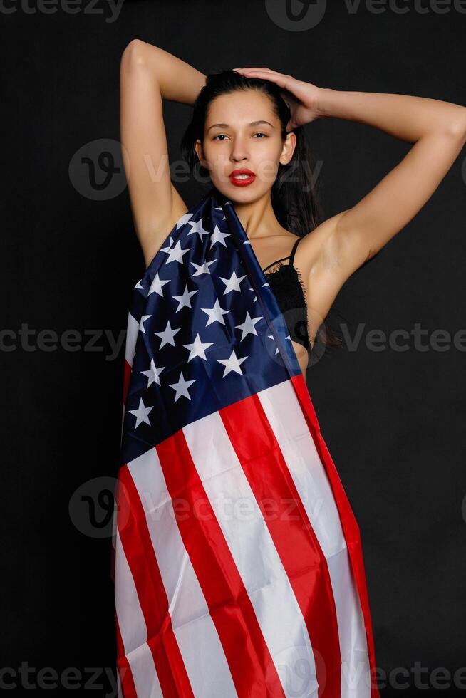 Portrait female athlete wrapped in American Flag against black background photo