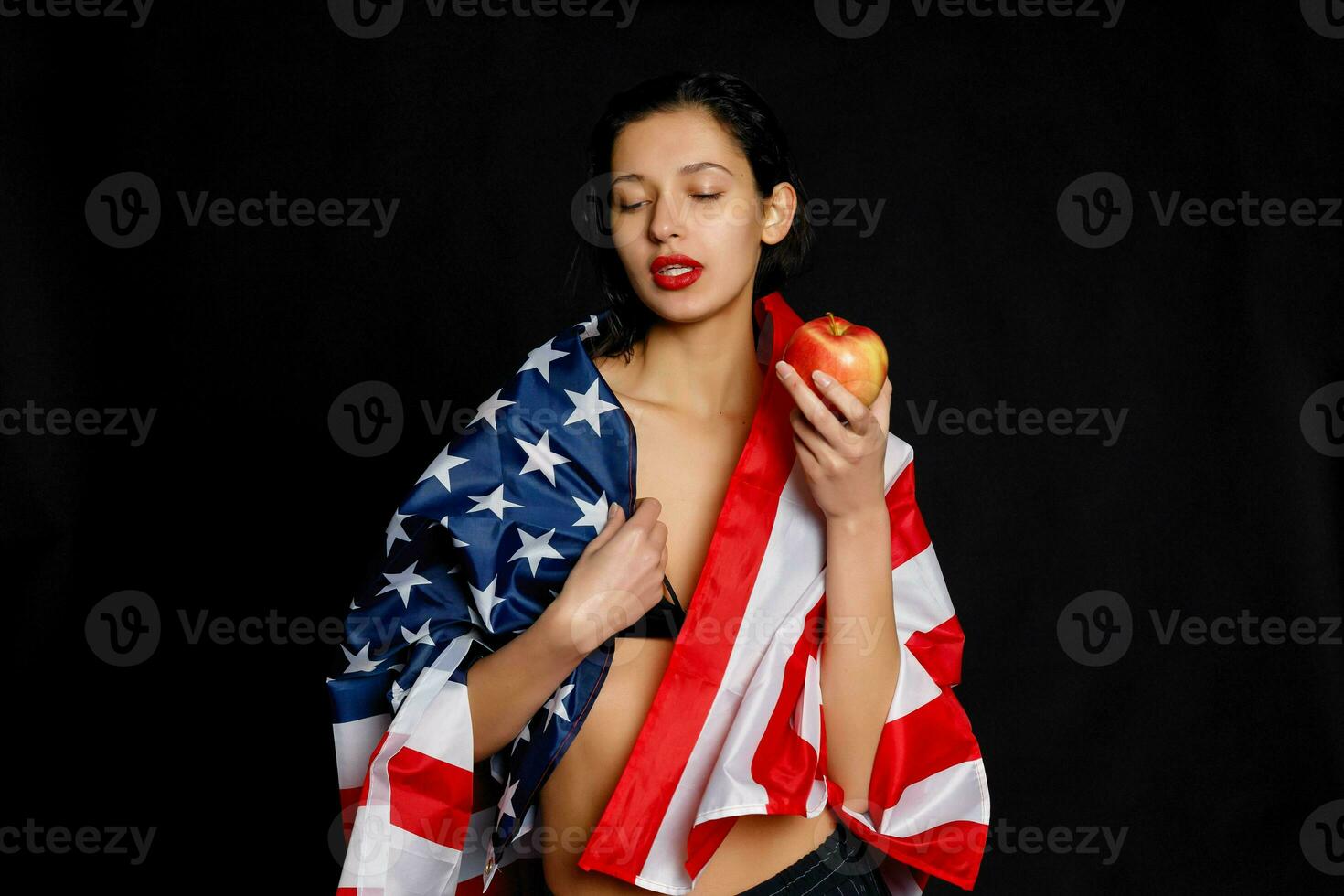 Portrait female athlete wrapped in American Flag against black background photo