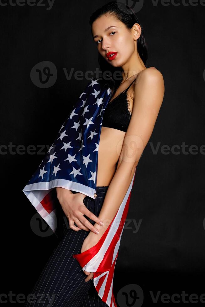 Portrait female athlete wrapped in American Flag against black background photo