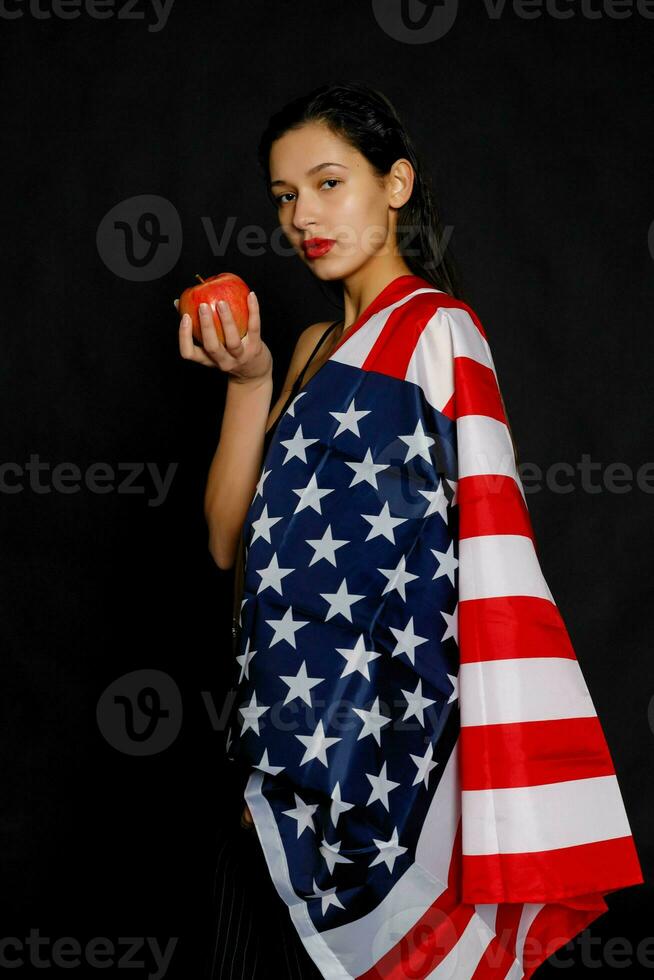 Portrait female athlete wrapped in American Flag against black background photo