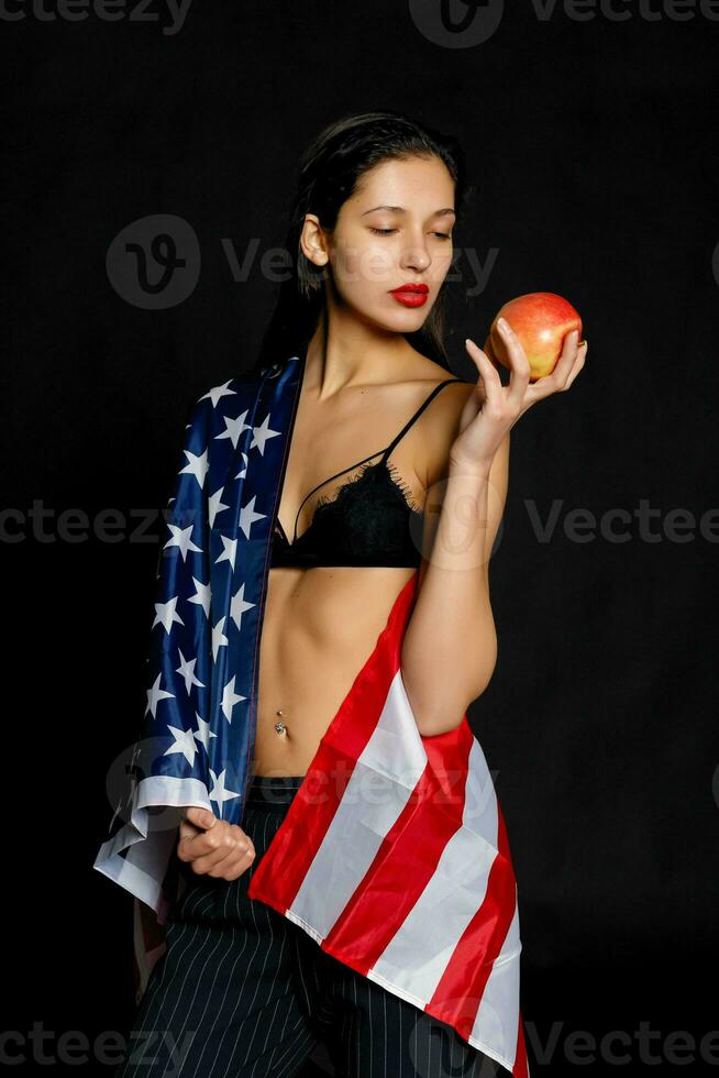 Portrait female athlete wrapped in American Flag against black background photo