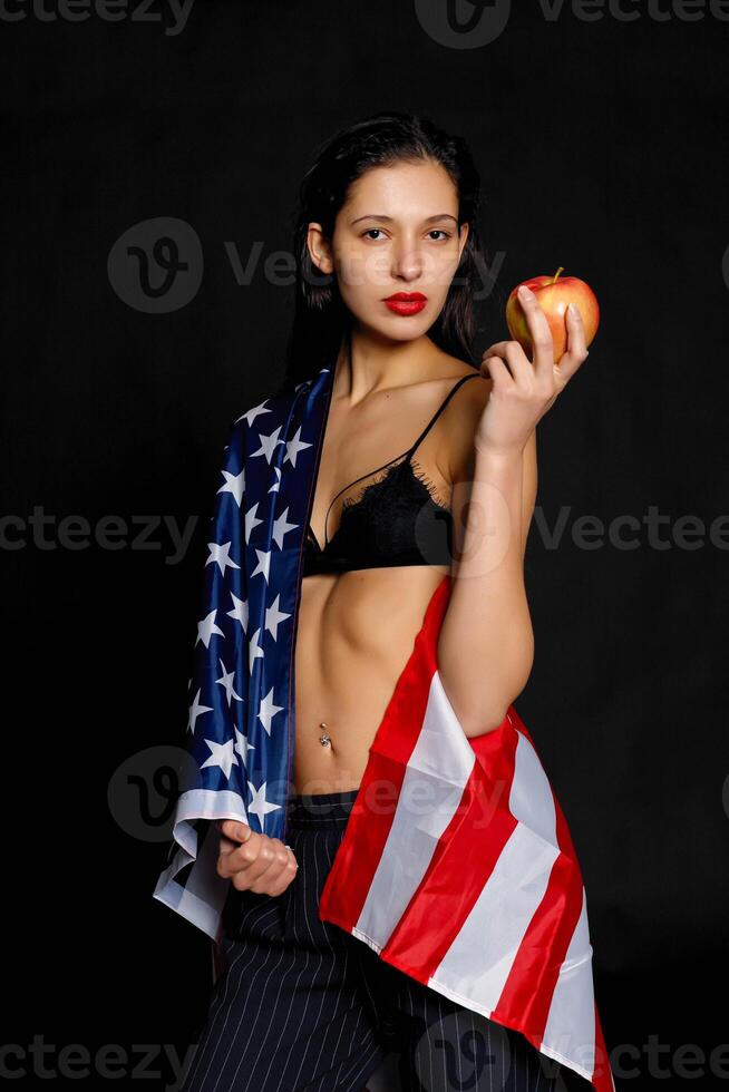 Portrait female athlete wrapped in American Flag against black background photo