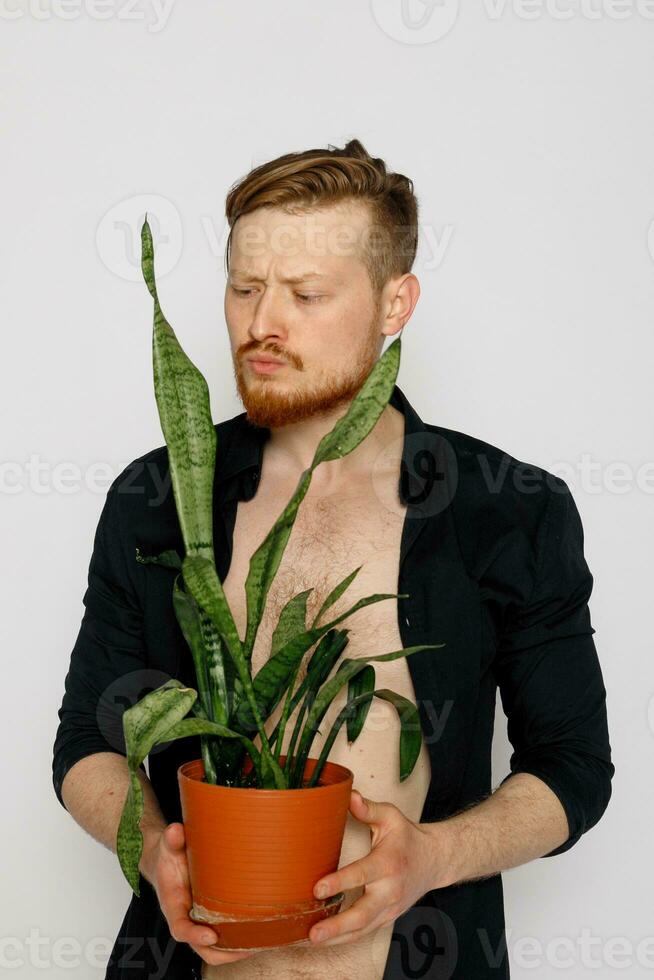 A young smiling man holds in his hands a small flower photo