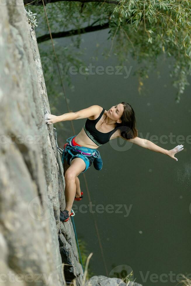 A girl climbs a rock. Woman engaged in extreme sport. photo