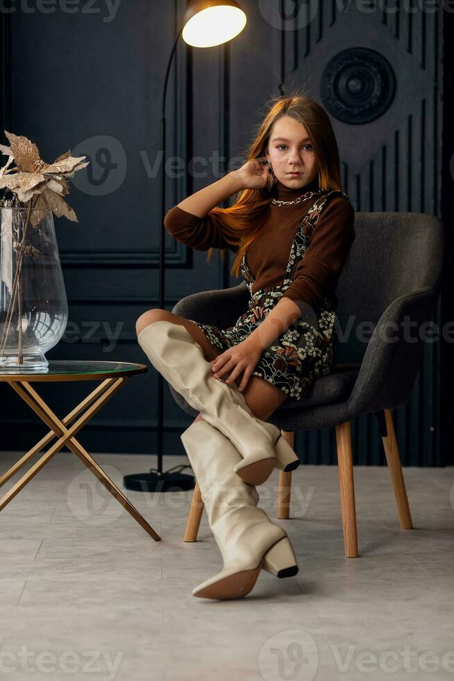 Charming girl with hair in posing in her mother's suede boots. photo
