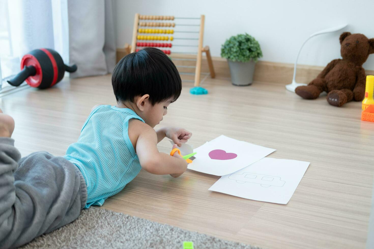 Asian boy using scissors to cut paper along lines Learning outside the classroom photo
