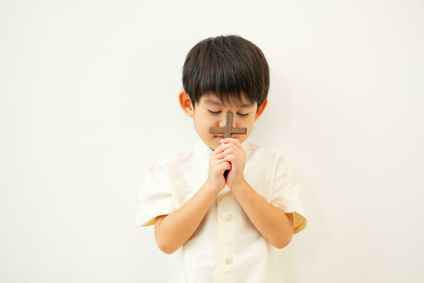 pequeño asiático chico Orando con participación el cruz, cristiano concepto foto