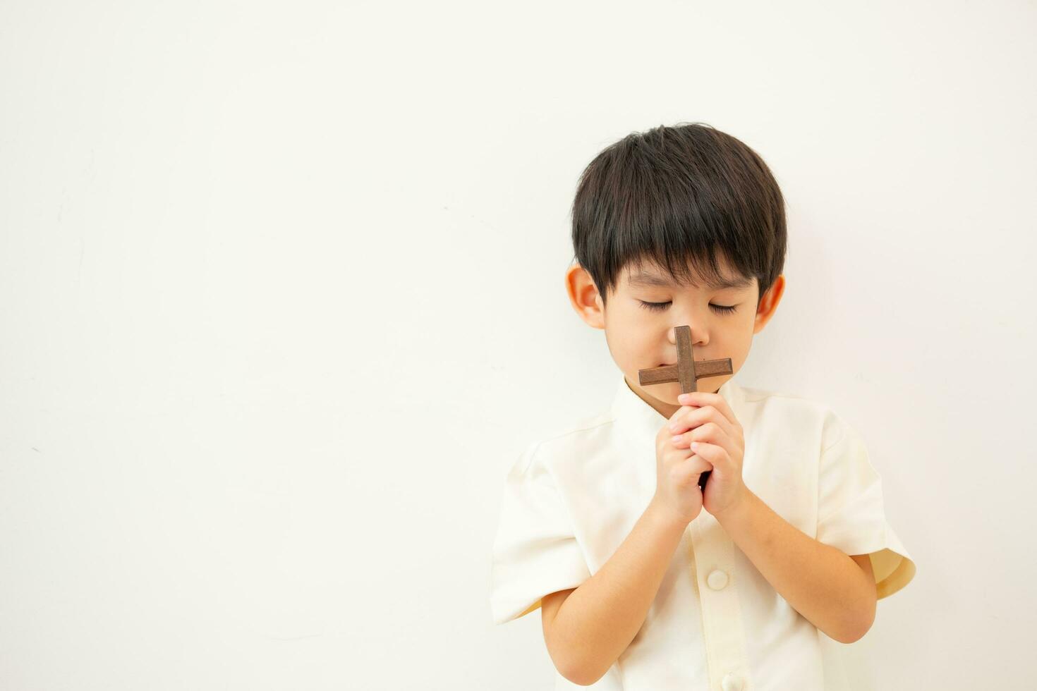 Little Asian boy praying with holding the cross, Christian concept photo
