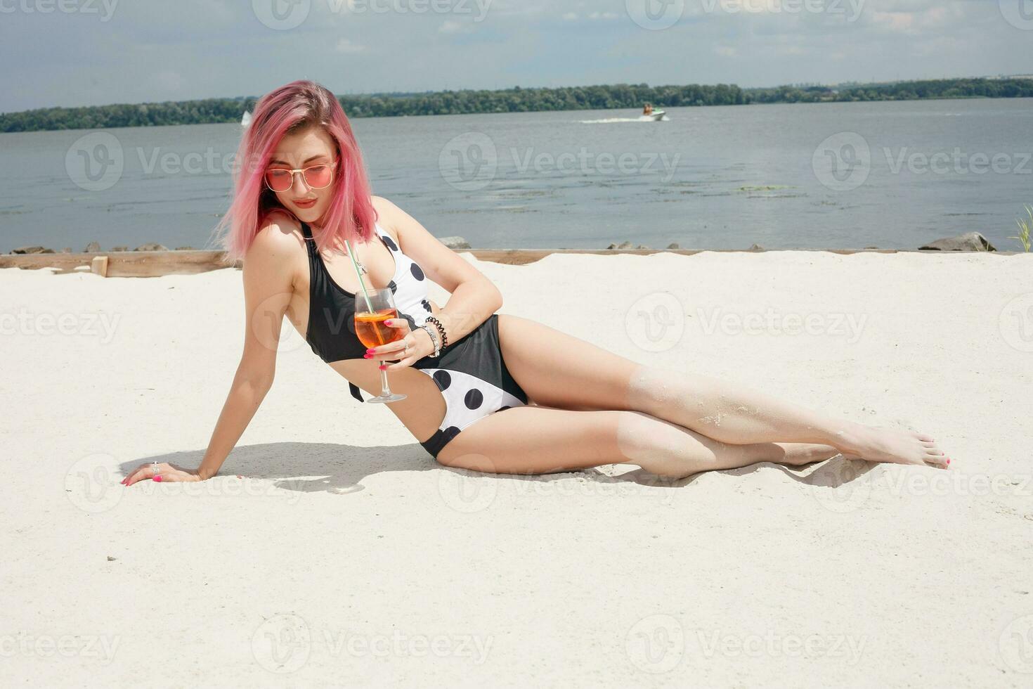 Young cheerful woman in swimsuit, toasting with cocktail, drinking fresh photo