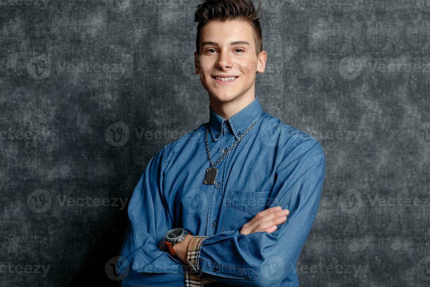 Man in denim shirt, arms on hips, gray background. photo
