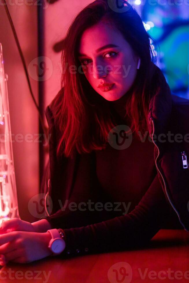 retrato de un niña en el antecedentes de un neón firmar de un tienda ventana foto