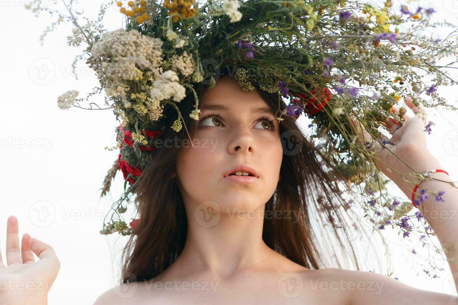 hermosa mujer con un guirnalda en su cabeza sentado en un campo en flores foto