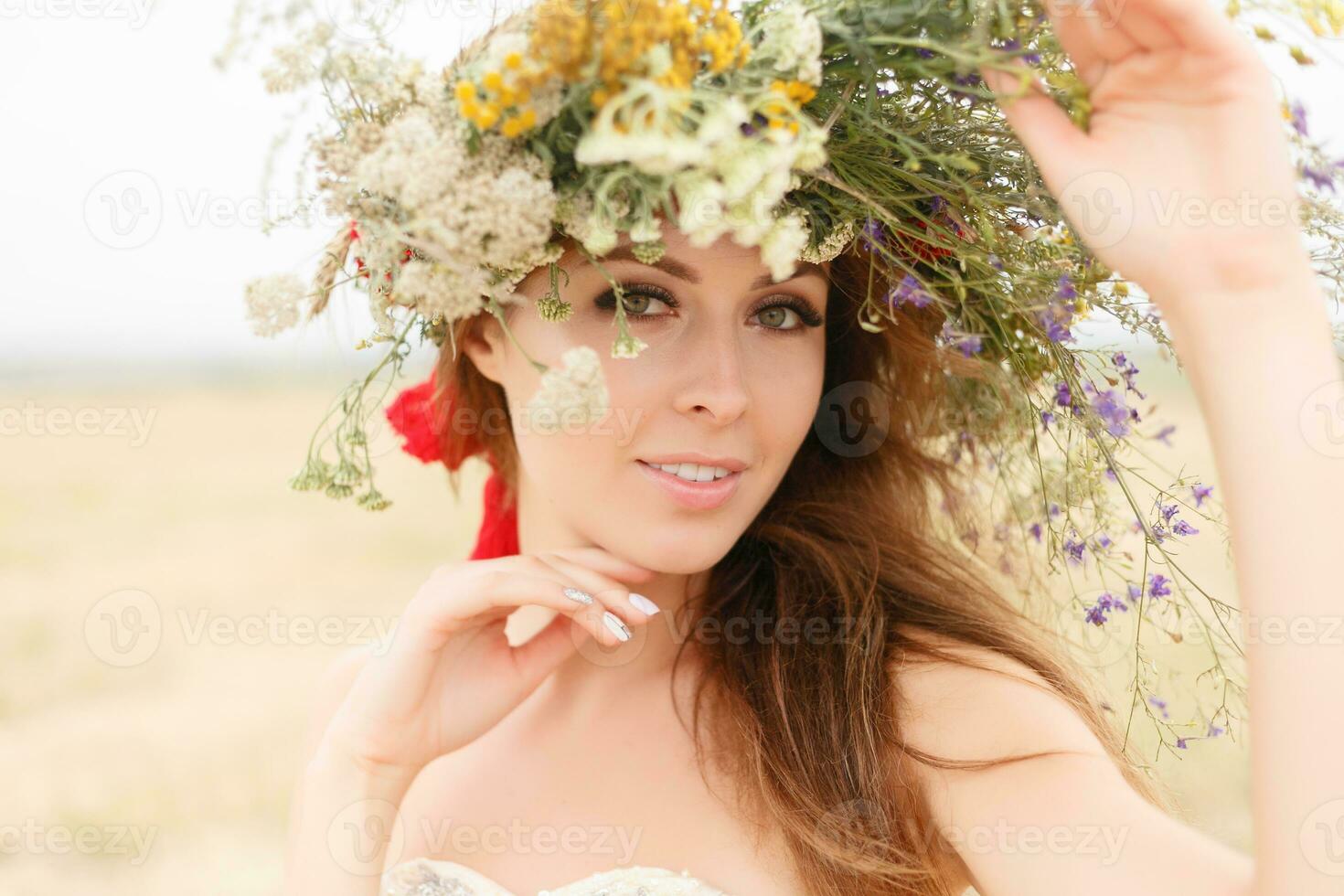 beautiful woman with a wreath on her head sitting in a field in flowers photo