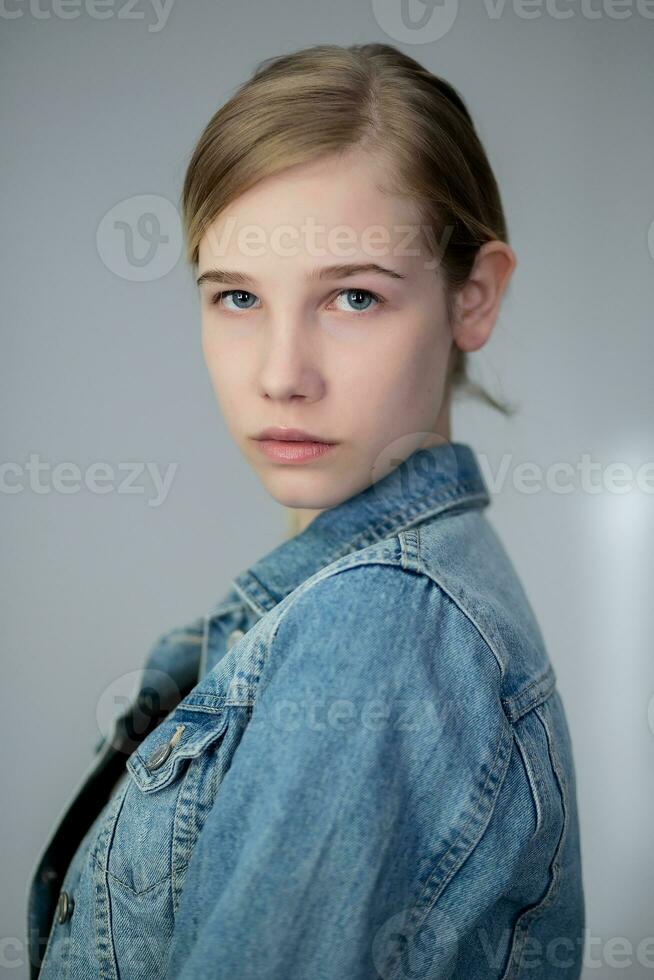 Portrait of a pretty young blond girl in a denim jacket photo