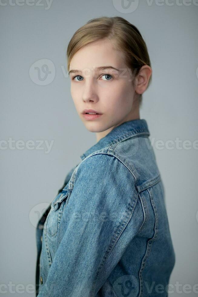 Portrait of a pretty young blond girl in a denim jacket photo