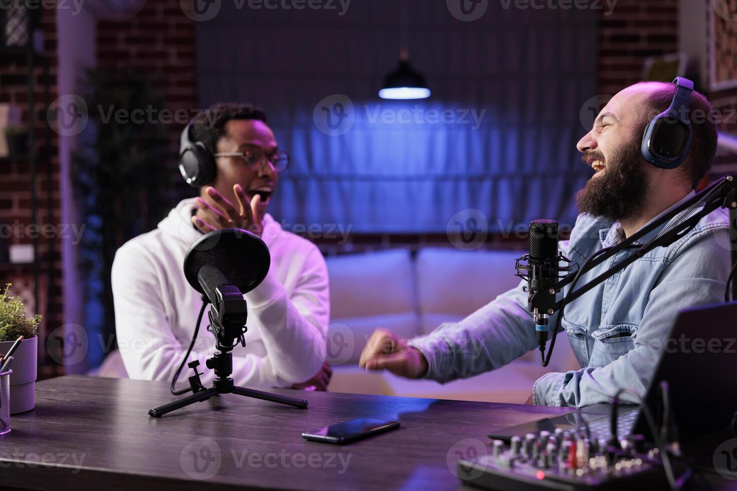 africano americano anfitrión atractivo en entretenido discusión con celebridad durante En Vivo corriente en profesional estudio, haciendo él reír. presentador utilizando alto calidad equipo a Produce comedia podcast foto