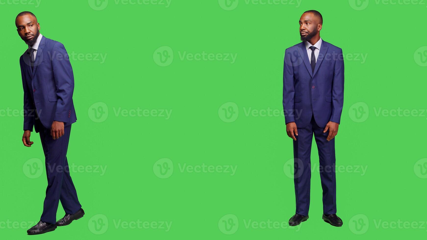 Young entrepreneur in business suit waiting on camera, looking around over full body greenscreen. Corporate worker feeling happy and stylish in studio, isolated green screen backdrop. photo