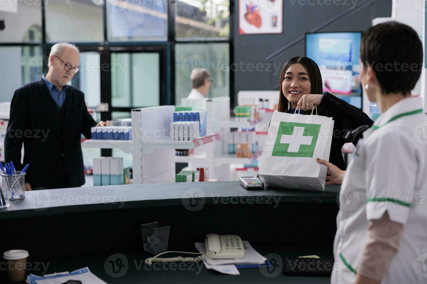 Drugstore cashier giving client shopping bag with medicine at checkout. Smiling casian woman taking purchase package from pharmaceutical employee at medical retail store counter desk photo