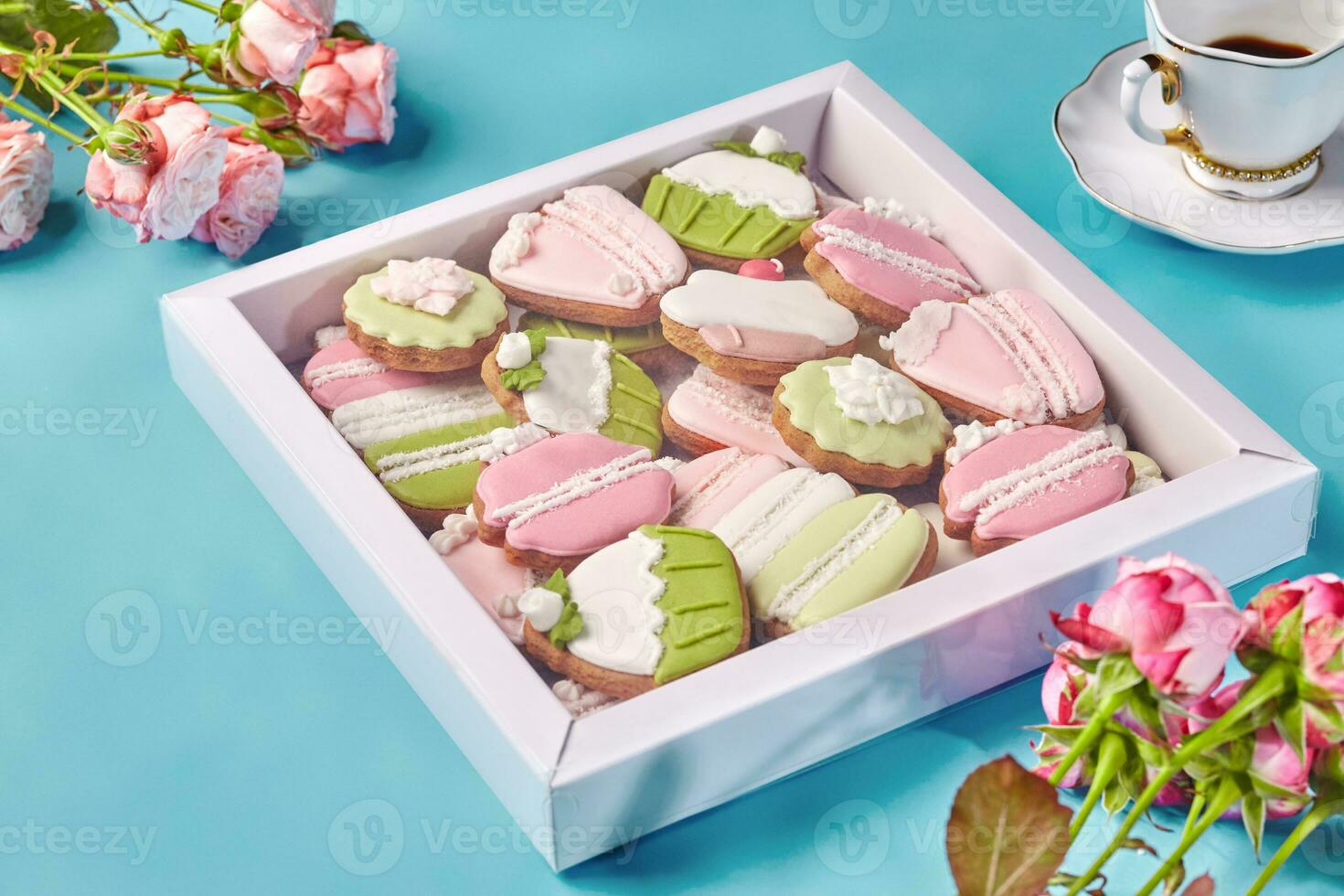 Box with gingerbread cookies with colorful sugar icing with cup of coffee and roses photo