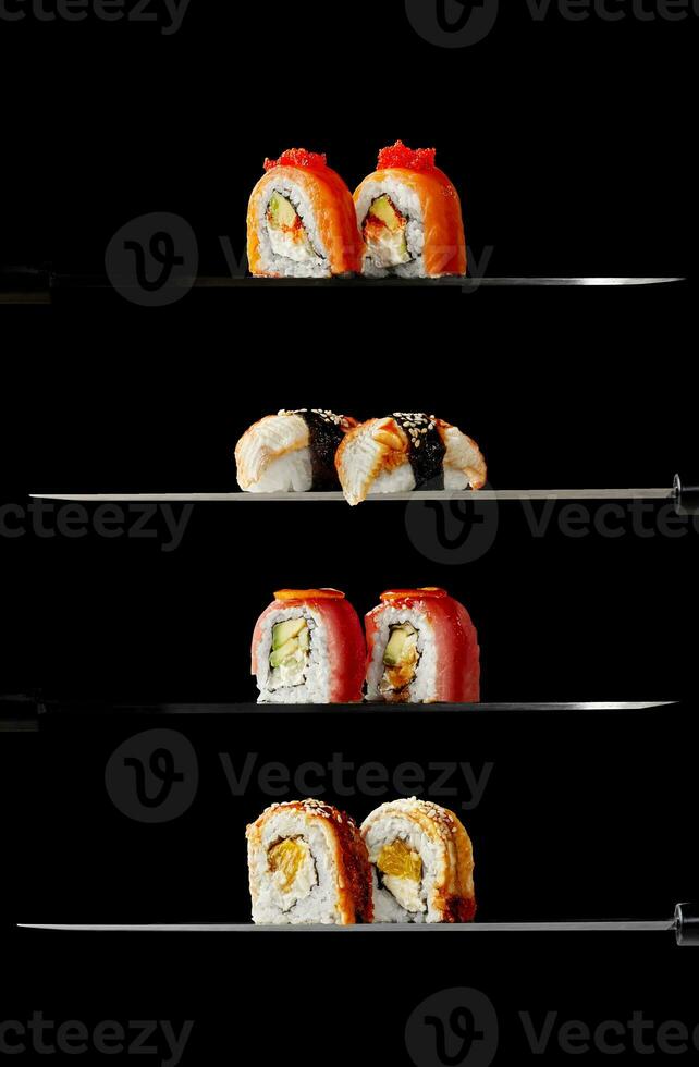 Philadelphia rolls with salmon, unagi rolls, uramaki with tuna and nigiri sushi with eel on knife blades on black background photo