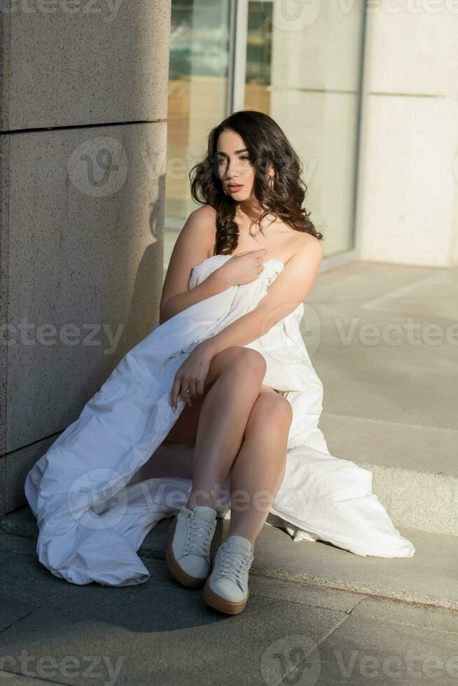 Young woman through the evening streets wrapped in a blanket. photo