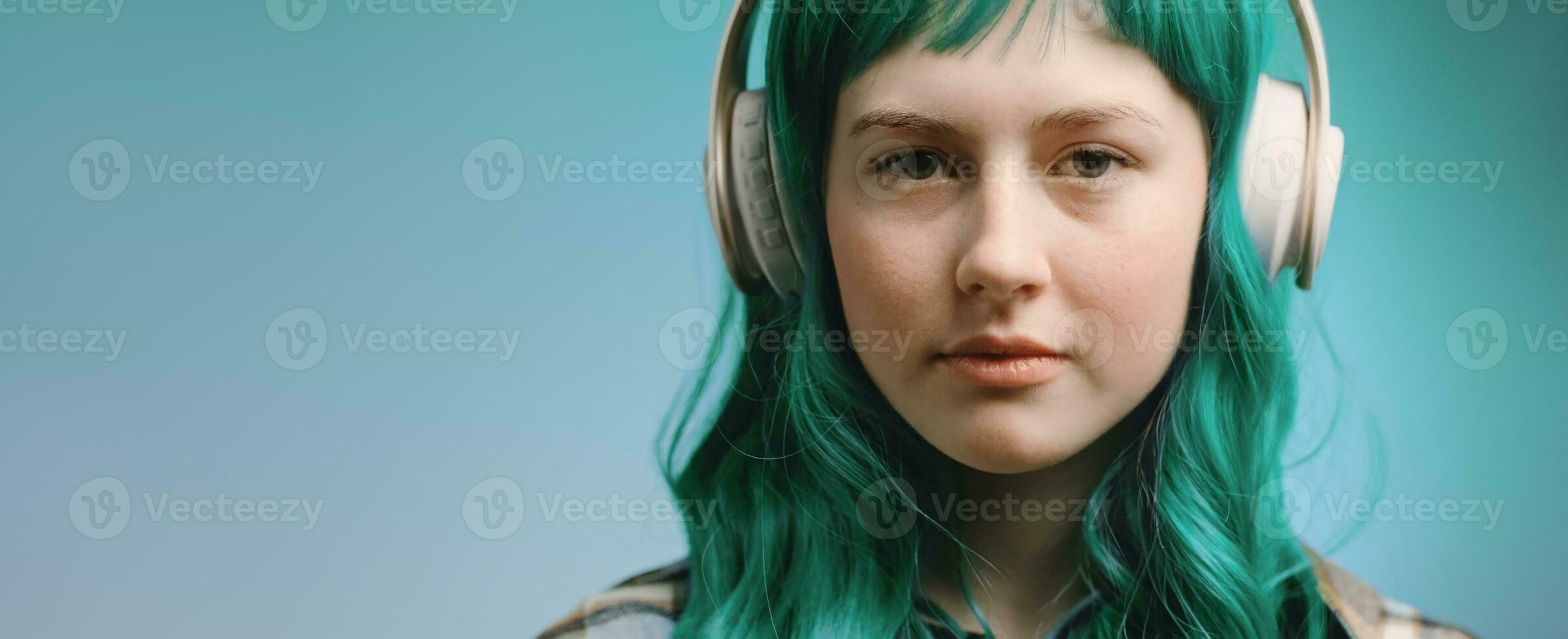 Gen Z beautiful young woman portrait. Teenager with green hair listens music in headphones, banner. photo